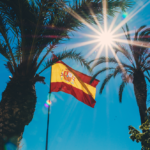 Una bandera de España entre dos palmeras.