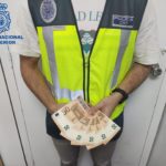 Un agente de la Policía muestra los billetes falsos con los que el joven detenido compró artículos en puestos ambulantes navideños en Palma - POLICÍA NACIONAL