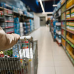 Mujer con un carrito de compras comprando en el supermercado.