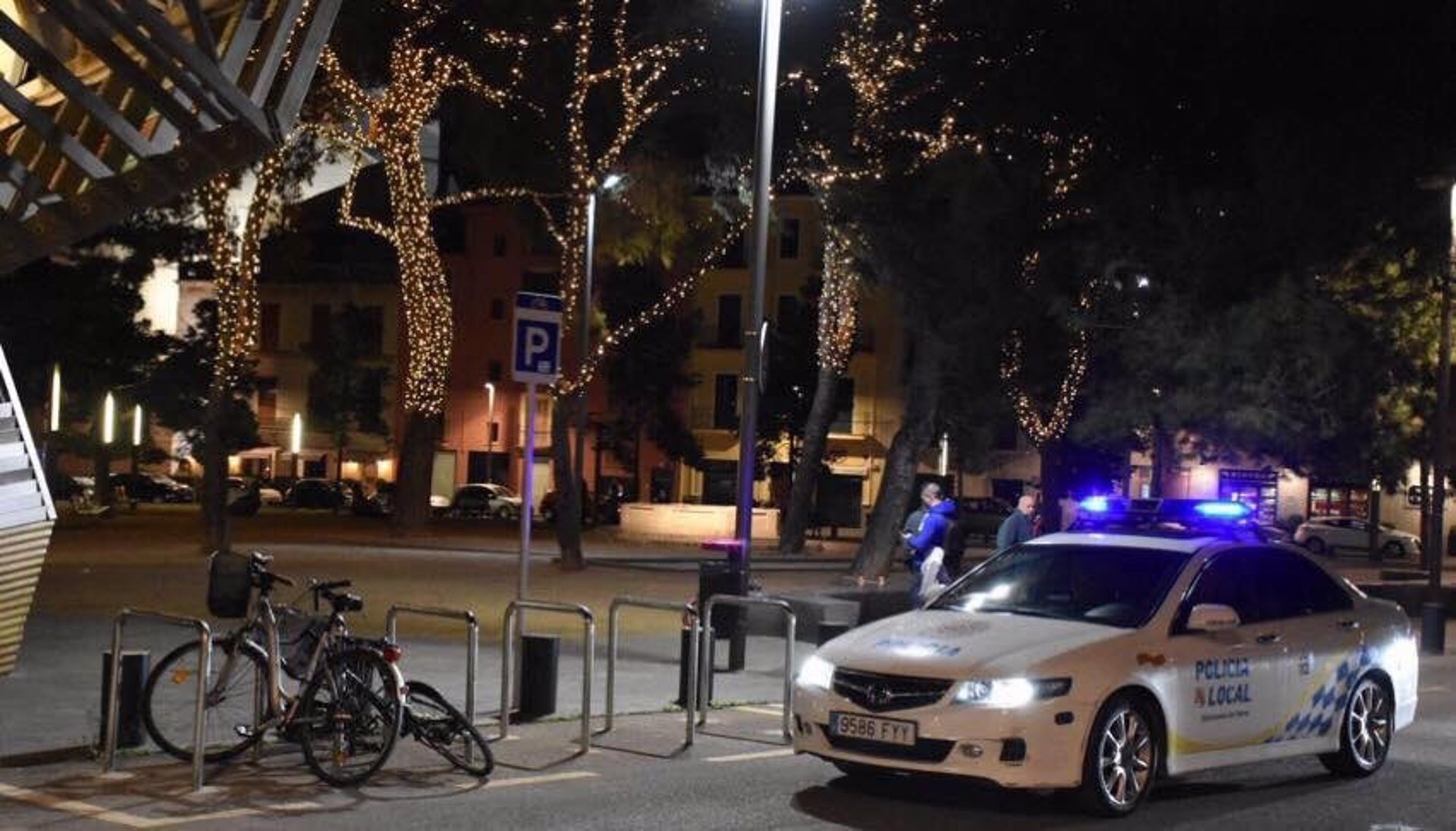 Coche de la Policía Local de Palma por la noche con la iluminación de Navidad al fondo.