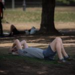 Una persona se cubre del sol bajo un árbol. - David Zorrakino - Europa Press
