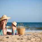 Madre e hija toman el sol en una playa.