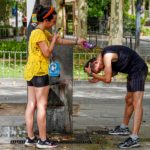 Una joven turista le hace una foto a un joven mientras le está refrescando la cabeza en Sevilla - Eduardo Briones - Europa Press - Archivo