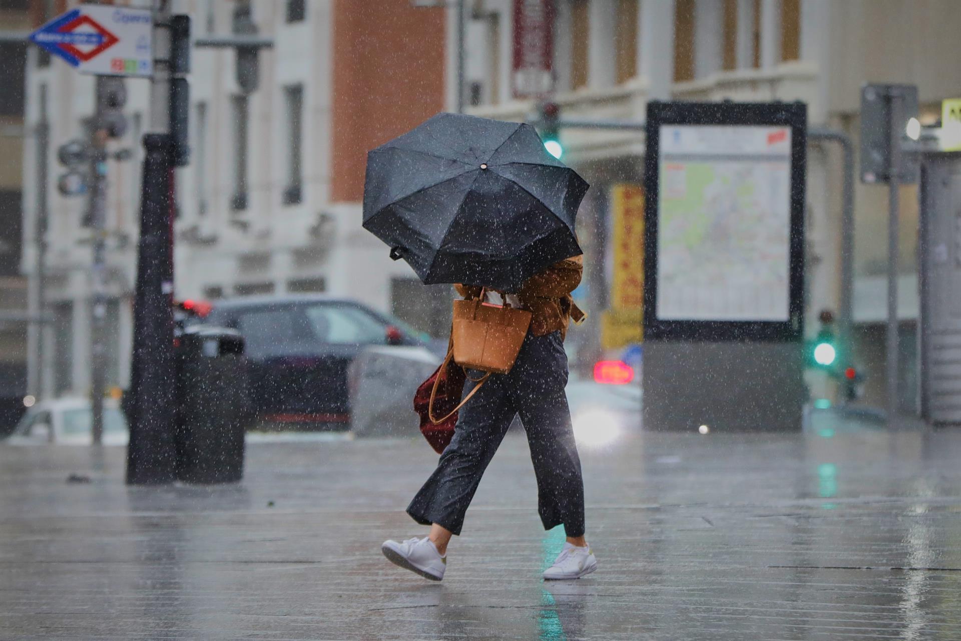 Una persona camina por el centro de la capital en una jornada marcada por las lluvias y la bajada de temperaturas, en Madrid, (España). - Jesús Hellín - Europa Press - Archivo