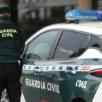Un agente de la Guardia Civil, de espaldas, de pie junto a un vehículo oficial. - GUARDIA CIVIL - Archivo