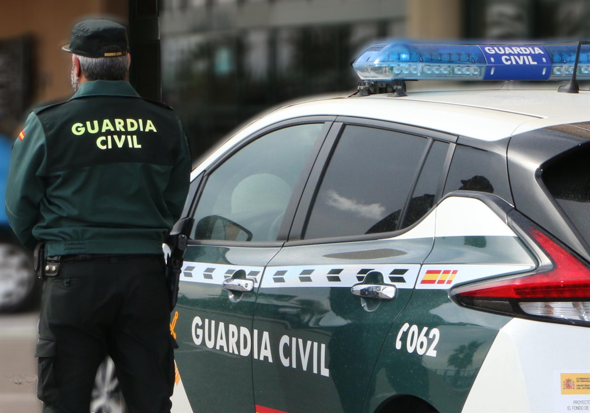 Un agente de la Guardia Civil, de espaldas, de pie junto a un vehículo oficial. - GUARDIA CIVIL - Archivo