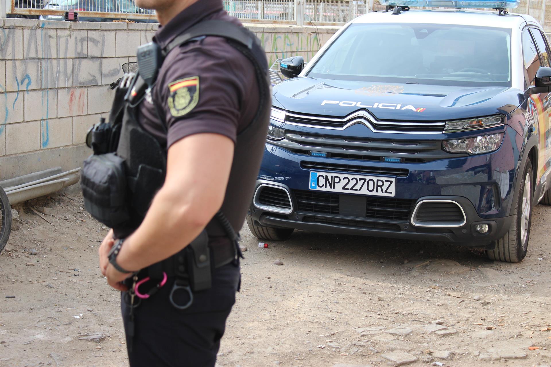 Imagen de un agente y un coche patrulla de la Policía Nacional. - POLICÍA NACIONAL